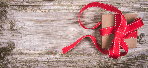 Gift with red ribbon on a wooden background