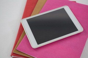 Digital tablet on book stack on white background