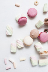 Top view colorful sweets on white background. Delicious macaroons, zephyrs and breakfast cereal are spread around, close up
