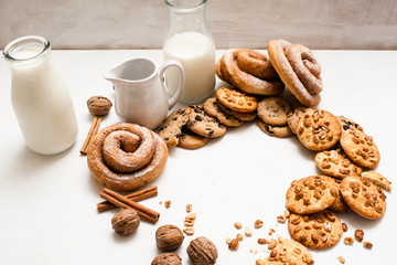 Culinary background of pastry organic breakfast, close up free space. Wholegrain scones and baked rolls with walnuts and cinnamon laying near bottle and pitcher of milk. Concept of home-baked shop
