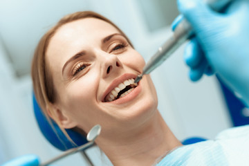 Naklejka premium A woman is sitting in a dental chair, doctors dentists bent over her