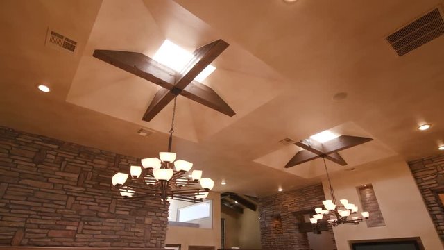 Unique Ceiling with Skylights and Chandelier Lights . panning left shot of a unique ceiling with wood beamed skylights and light fixtires in a brown modern home
