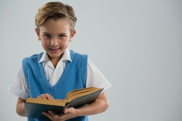 Smiling schoolboy reading book