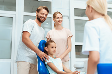 Obraz premium Dziewczyna w recepcji dentysty. Uśmiecha się i rozmawia z lekarzem. Obok jej rodziców
