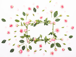 Round frame made of pink and beige roses, green leaves, branches, floral pattern on white background. Flat lay, top view. Valentine's background