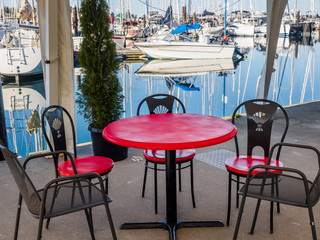 Table and chairs under the tent overlooking marina with yachts and sailboats