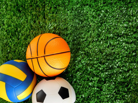 Balls For Soccer, Basketball And Volleyball Are Lying On The Green Grass. Different Sports Concept