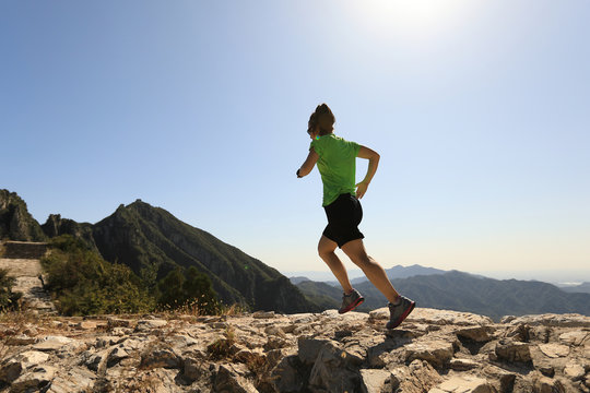young fitness woman trail runner running on top of mountain