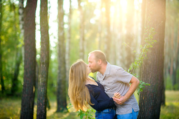 two lovers rest in the open air at sunset, hug and kiss