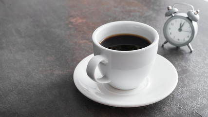 Cup of coffee with alarm clock