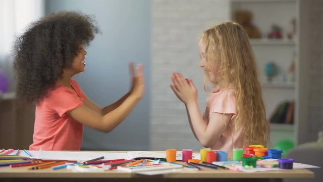 Young multiracial ladies having fun and clapping hands at home, leisure time