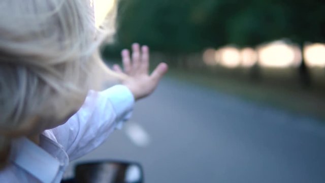 Kid with hair in the wind riding in the car.