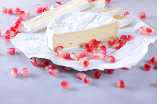 Camembert cheese, sliced cheese, lots of cheese with pomegranate seeds on white background