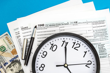 Tax forms with clock and money on blue background. Business concept.