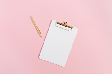 Clipboard and golden pen on pink background. Minimal flat lay mock up.