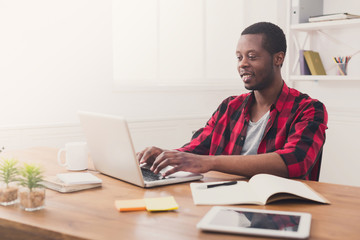 Happy black businessman in casual office, work with laptop