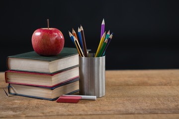 School supplies and books stack with red apple on top  
