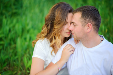 happy young couple walking in beautiful park, sitting on grass and hugging