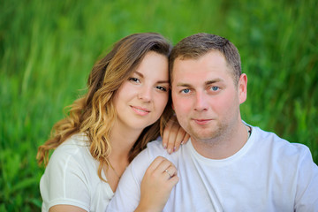 happy young couple walking in beautiful park, sitting on grass and hugging