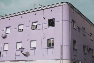 Detalle de fachada de edificio morado haciendo esquina entre dos calles.