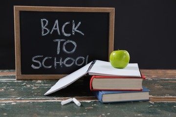 Books, apple and slate board with back to school text