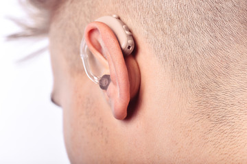 Young man hearing impaired dressing the hearing aid. At isolated white background.