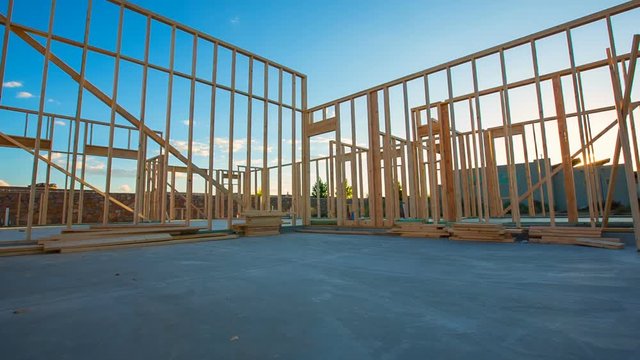 Residential Home Construction Site Framed at Sunset Wide. view moves right on a wide shot of a new home construction with some framed wall up during sunset
