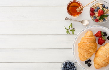 Continental breakfast with croissants and berries on white wood