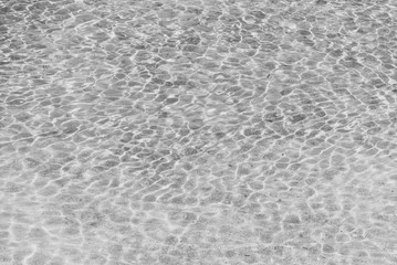Refraction of light in clear water with small waves. Background. Black and white photo