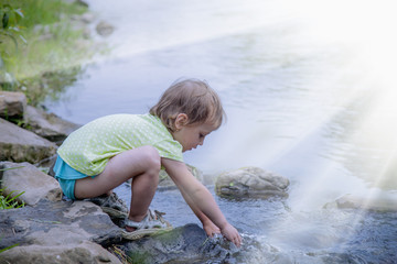 Little girl having fun by  mountain  river at summer (Holiday, rest, happy childhood, games, nature concept)