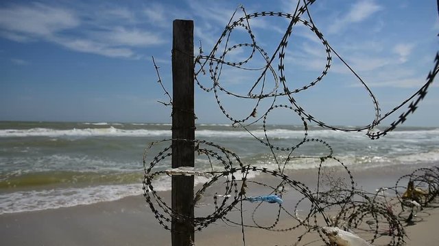 Fence with barbed wire on background of sea