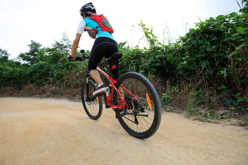 Fototapeta premium young woman riding mountain bike on forest trail