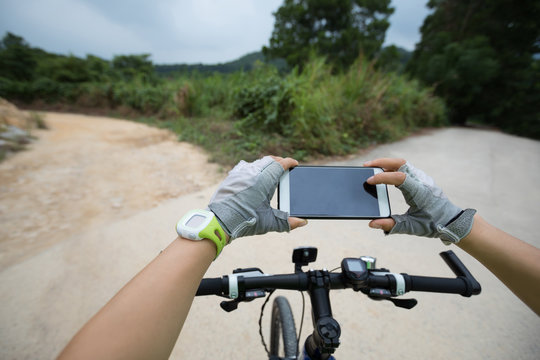 cyclist use smatphone taking photo on mountain trail