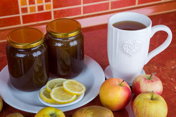 Glass cup of tea with lemon and honey. Honey in the glass jar.