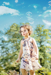 Cute little girl playing soap bubbles