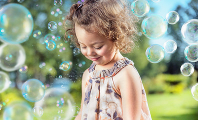 Cute, little girl among hundreds of soap bubbles