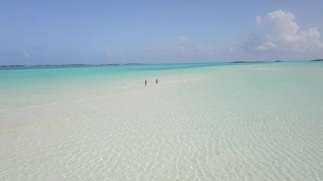 Young people walked along shore beach with turquoise water and white sand