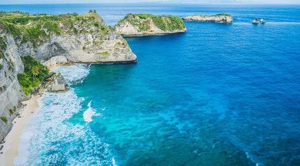 Rock in the ocean with beautiful palms behind at Atuh beach on Nusa Penida island, Indonesia