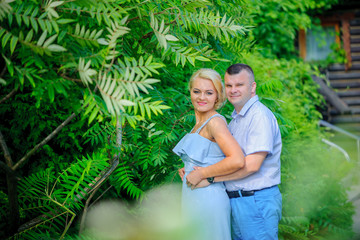 Fototapeta na wymiar adult couple hugging standing on the background of beautiful greenery