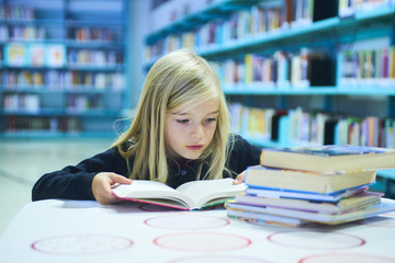 Child girl with book in public library