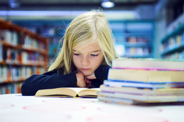 Child girl with book in public library