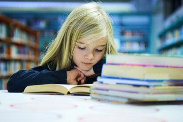 Child girl with book in public library