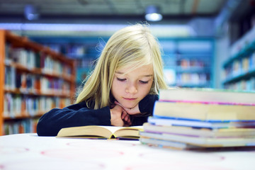 Child girl with book in public library
