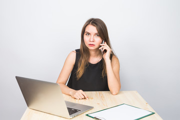 business concept - businesswoman talking on the phone in office and working on laptop.