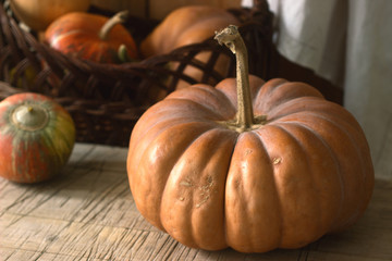 Ripe pumpkins on a wooden background and in a basket. Rustic style, selective focus.