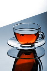 Cup of tea with plate on the reflective surface.Creative reflection.Gradient background.Copy space