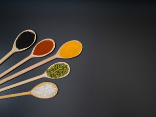 Top view mix indian spices in wooden spoons  on a black background