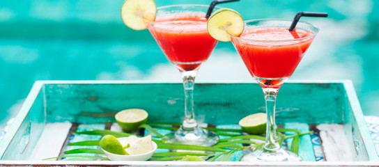 Strawberry margarita cocktail on colorful wooden background with palm leaf. Copy space