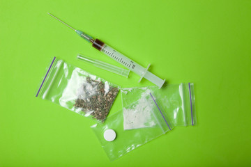 Heroin, cocaine, marijuana and ecstasy on a green background.