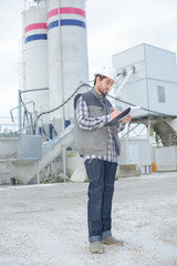 Man on construction site writing on clipboard